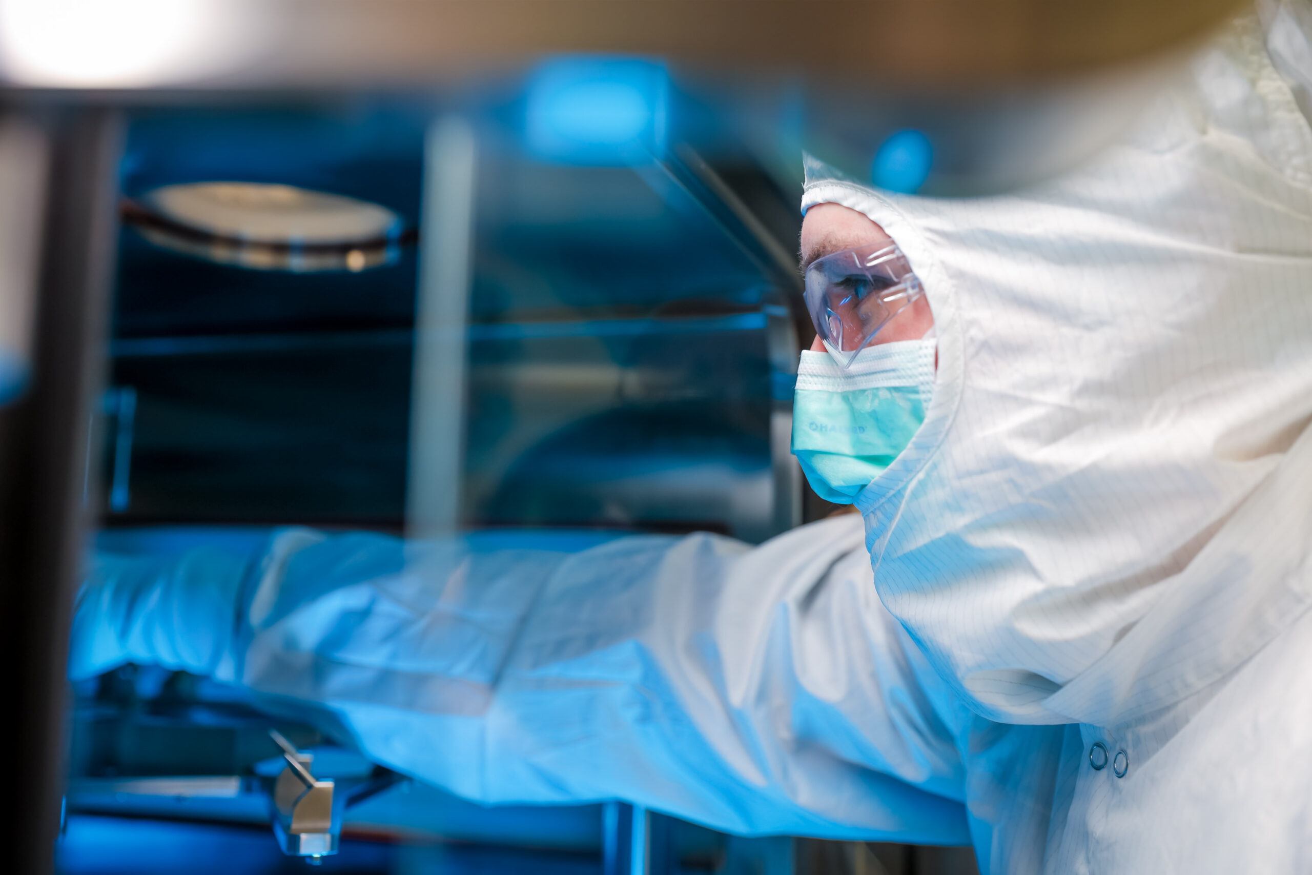 A scientist at Forge Biologics in full PPE attending to a client's drug substance in one of our cGMP suites.
